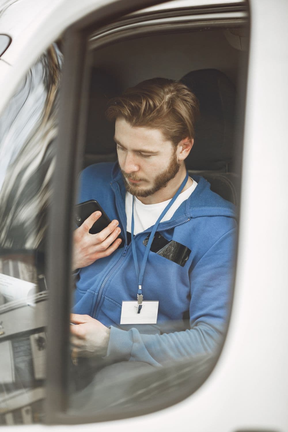 Fahrer im Transporter bedient die DocuFleet App auf dem Smartphone