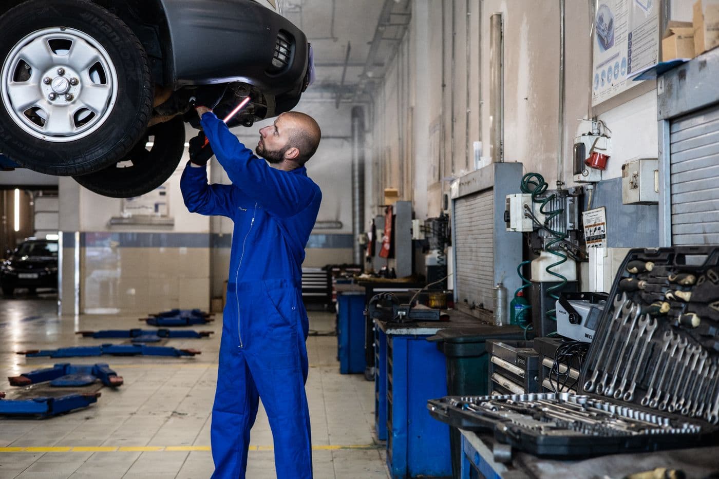 Mechaniker prüft ein Fahrzeug auf der Hebebühne von unten